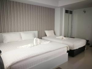 two beds in a hotel room with white sheets at Phimai Residence in Pi Mai