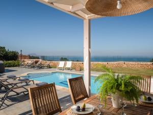 a patio with a table and chairs and a swimming pool at Anemolia Seaview Villa, Private Pool & Lush Garden, By ThinkVilla in Gerani
