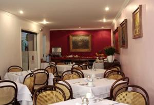a restaurant with white tables and chairs and a red wall at Hotel Pousada Minas Gerais in Ouro Preto