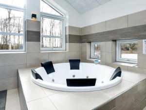 baño con bañera blanca grande y ventanas en 14 person holiday home in Str by en Strøby