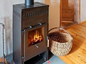 a stove with a fire in a room with a basket at 4 person holiday home in Sk rblacka in Skärblacka
