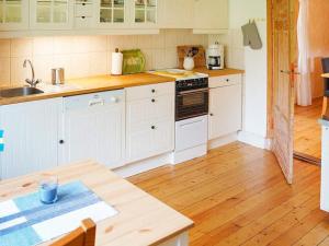 a kitchen with white cabinets and a wooden floor at 4 person holiday home in Sk rblacka in Skärblacka