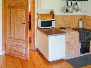 a kitchen with a stove and a microwave on a counter at 4 person holiday home in Sk rblacka in Skärblacka