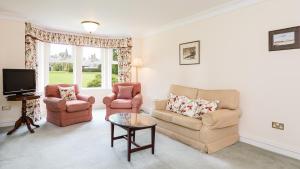 a living room with two chairs and a tv at Ballathie House Hotel in Perth