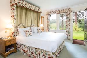 um quarto com uma grande cama branca e janelas em Ballathie House Hotel em Perth
