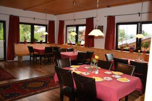 ein Esszimmer mit roten Tischen, Stühlen und Fenstern in der Unterkunft Gästehaus Wöll in Alpbach