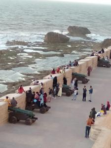 een groep mensen op het strand bij de oceaan bij Appartements la grotte in Essaouira