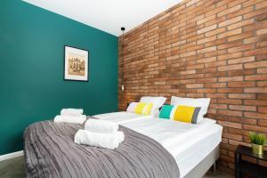 two beds in a room with a brick wall at Apartments Gdańsk Rajska by Renters in Gdańsk