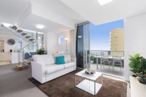 a living room with a white couch and a table at SK1 - 2 level 2 Bedroom Skyline SkyHome in Brisbane