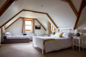 Un dormitorio abuhardillado con dos camas y una ventana. en The Old Forge B&B, en Sark 41 fotos más