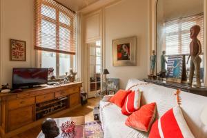 a living room with a white couch with red pillows at Veeve - Vintage & Eclectic in the 17th in Paris