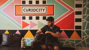 a man sitting on the floor with a bag at CURIOCITY Backpackers Johannesburg in Johannesburg