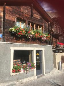 un bâtiment avec des boîtes de fleurs sur son côté dans l'établissement Schirle, à Zermatt