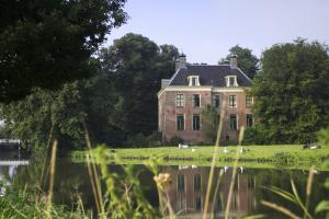 uma casa velha numa colina ao lado de um corpo de água em Stayokay Hostel Utrecht - Bunnik em Bunnik