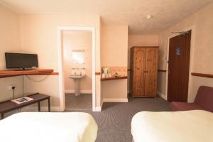 Pinegrove Hotel في كارلايل: غرفة الفندق بسرير ومغسلة