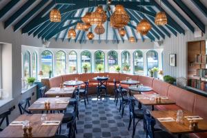 a restaurant with tables and chairs and windows at The Swan, Streatley, Berkshire in Streatley