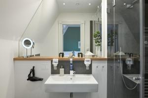 ein weißes Badezimmer mit Waschbecken und Dusche in der Unterkunft FIRST im FIRST Sellin, Penthouse Paradies am Meer in Ostseebad Sellin