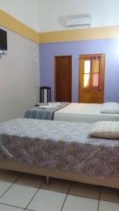 two beds in a room with purple walls at Hotel Pousada Paraíso das Águas in Barreirinhas