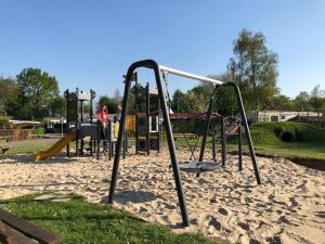 um parque com um parque infantil com dois baloiços em Travelzeeland vakantiehuizen em heinkenszand