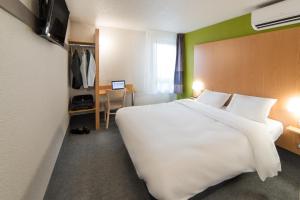 a hotel room with a large white bed and a desk at B&B HOTEL Verdun in Verdun-sur-Meuse