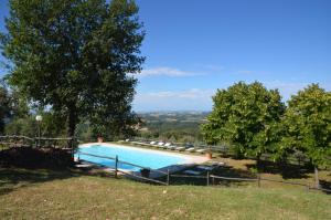 a large swimming pool in a field with trees at Borgo Cortinova Marrocco in Rapolano Terme