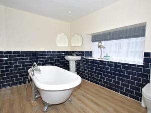a blue tiled bathroom with a tub and a toilet at The Hood Arms in Kilve