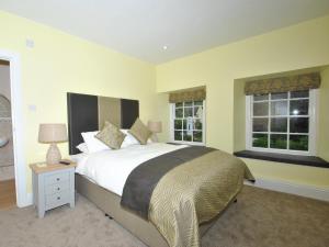 um quarto com uma cama grande e 2 janelas em The Hood Arms em Kilve