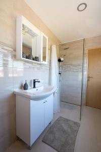 a white bathroom with a sink and a shower at OPG HORVAT SOBE ZA ODMOR in Daruvar