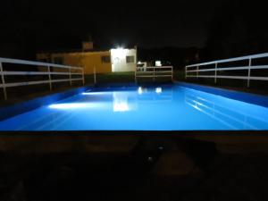 une grande piscine éclairée la nuit dans l'établissement Cabañas Luz de Luna, Comuna San Roque-Punilla, à Córdoba