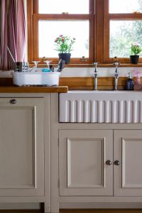 Una encimera de cocina con un fregadero y una ventana. en The Old Forge B&B, en Sark