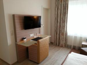 a hotel room with a desk with a television on a wall at Hotel Restaurant Itzumer Paß in Hildesheim