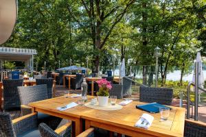 a wooden table with chairs and tables and trees at INSELHOTEL Potsdam in Potsdam