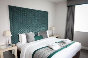 um quarto com uma cama grande e uma cabeceira verde em The Malvern em Great Malvern