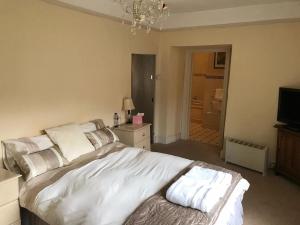 1 dormitorio con 1 cama blanca grande y TV en The Carew Arms en Taunton