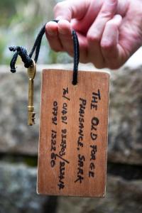 a person holding a wooden tag with a key at The Old Forge B&B in Sark