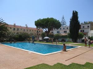 une femme assise dans une piscine d'un complexe dans l'établissement Estrela Mar Marina Villa, à Quarteira