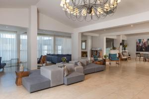 ein großes Wohnzimmer mit Sofas und einem Kronleuchter in der Unterkunft Kassandra Bay Resort, Suites & Spa in Vassilias