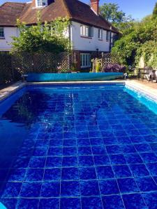 a swimming pool with blue tiles in front of a house at Hazelwick in Hookwood