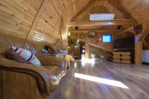 a living room with a leather couch and a tv in a cabin at Wooden Attic Suite in Braşov