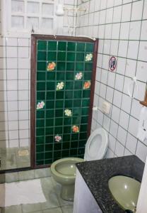 a bathroom with a toilet and a green tile wall at Paradise Hostel Ilha Grande in Abraão