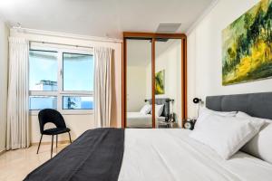 a bedroom with a bed and a chair and a window at Picturesque 3BR Apt w Balcony & Parking Near Beach by Sea N' Rent in Tel Aviv
