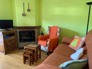 sala de estar con sofá, silla y TV en BPIRINEOS-La Borda, en Benasque