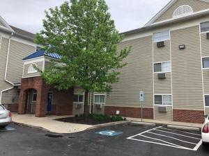 a building with a tree in a parking lot at InTown Suites Extended Stay Columbus OH - Dublin in Columbus