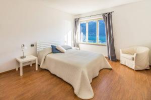ein Schlafzimmer mit einem Bett, einem Stuhl und einem Fenster in der Unterkunft Miralago Apartments Villa Rosa Lake View in Bellagio