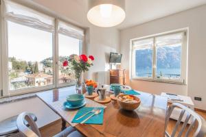 ein Esszimmer mit einem Tisch und 2 Fenstern in der Unterkunft Miralago Apartments Villa Rosa Lake View in Bellagio