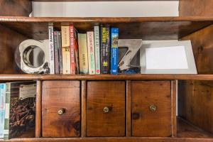 a wooden book shelf with books and a laptop on it at Miralago Apartments Villa Rosa Lake View in Bellagio