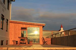 a wooden deck with a table and a chair on a building at Hotel Breidavik in Breiðavík