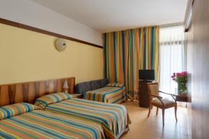 a hotel room with two beds and a television at Sporthotel Olimpo in Garda