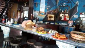 a restaurant with a counter with plates of food at Skandalo Pub Pousada in Rio das Ostras