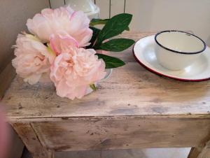 una mesa con una taza y flores rosas. en Acogedor apartamento VALLE DEL JERTE, en Piornal